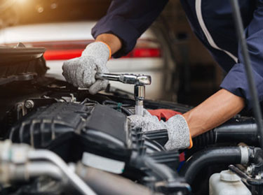 Mechanic servicing A/C components under a car's hood