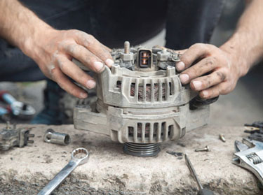 Mechanic holding a removed alternator on a workbench