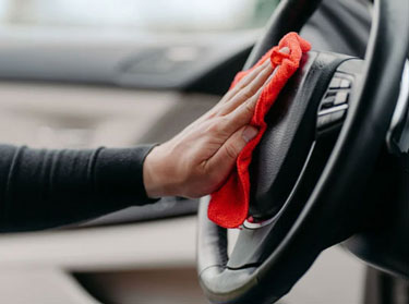 Detailer wiping a steering wheel with a microfiber cloth