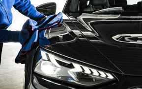 Detailer polishing the headlight of a black car