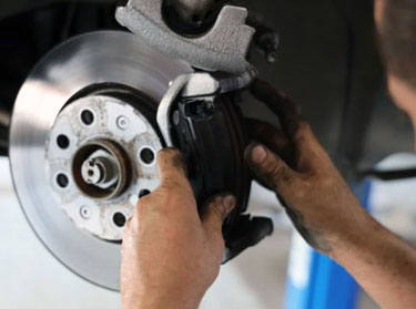 Mechanic fitting a brake pad beside a brake rotor