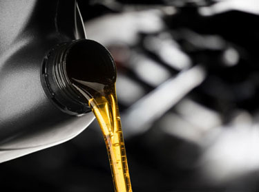 Fresh motor oil pouring into an engine
