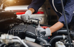 Mechanic working on the A/C components under a car hood
