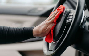 Detailer wiping down a steering wheel with a microfiber cloth