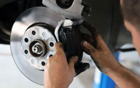 Mechanic fitting a brake caliper over a brake rotor